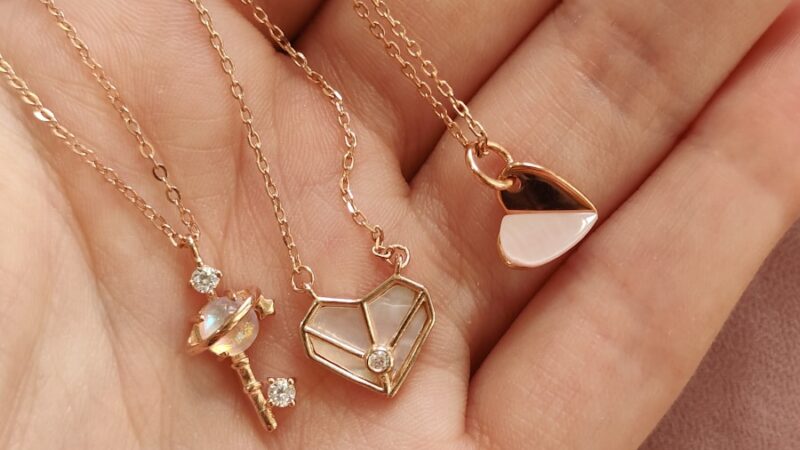 a woman's hand holding four different necklaces